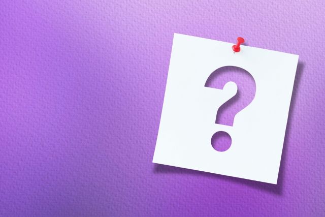紫の背景の前にあるハテナマーク